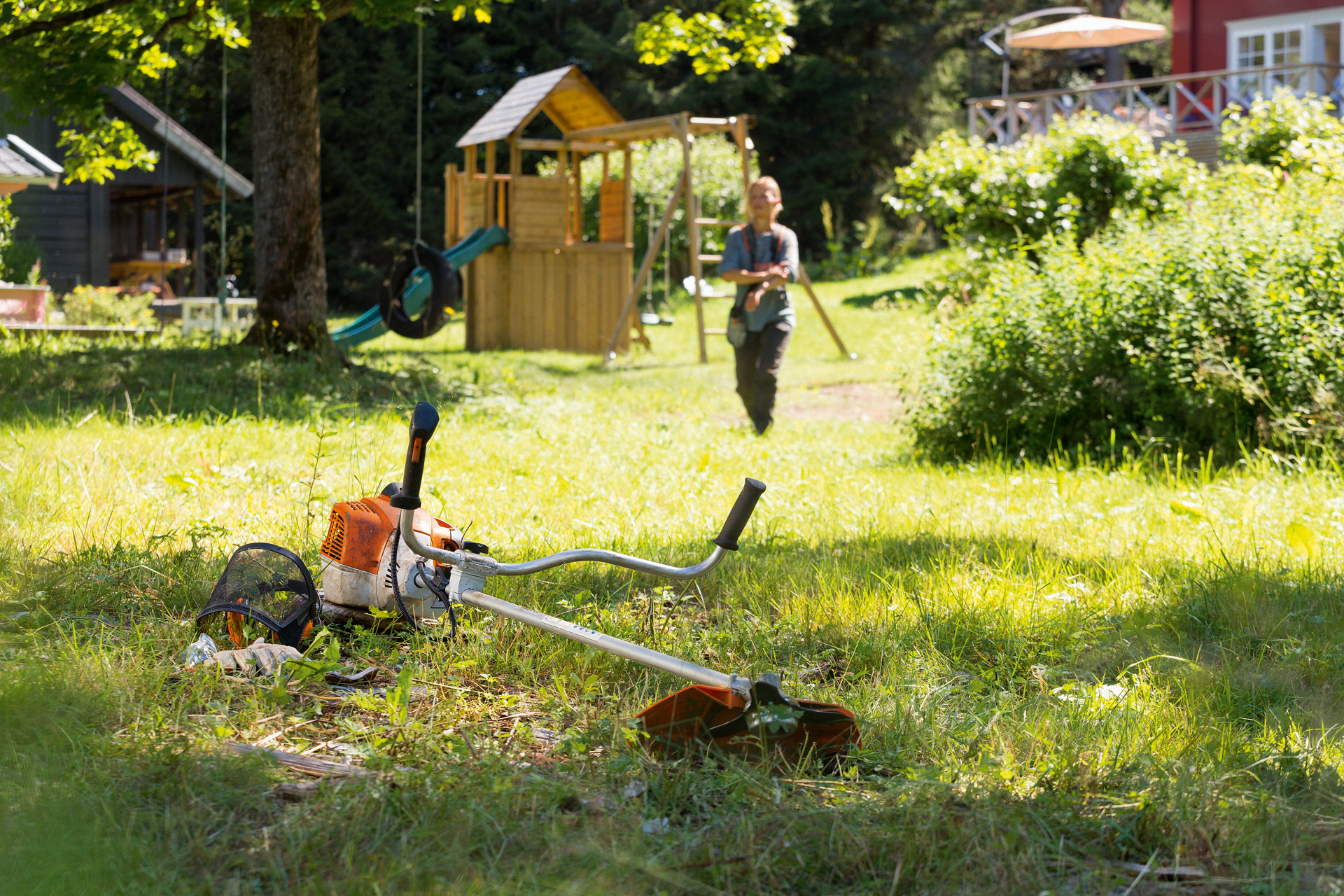 En STIHL FS 240 ryddesag i gress, foran en mann som gjør seg klar til å vedlikeholde den